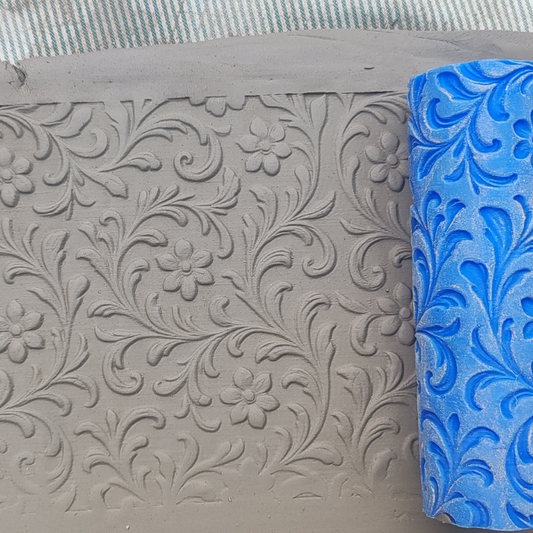 Gray embossed surface with floral pattern next to a blue roller with similar design